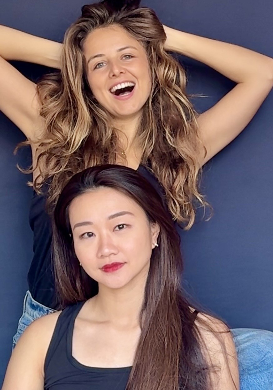 Selina and Lalia, founders of Pebble Theatre, in a playful portrait against a deep blue wall.