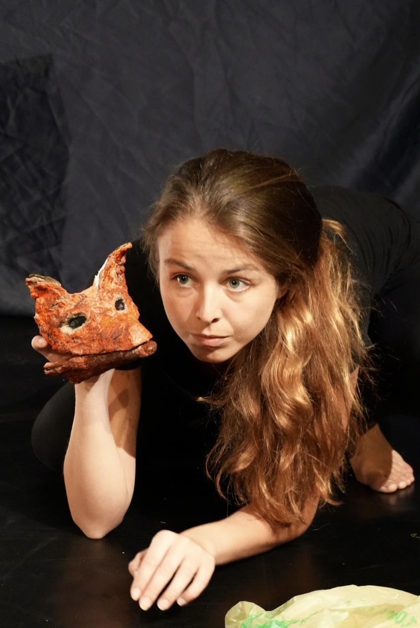 A performer wearing a fox mask, poised and watchful, in Out of the Bin.