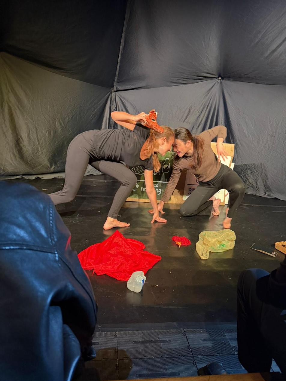 A physical duet between the two performers, bodies intertwined.