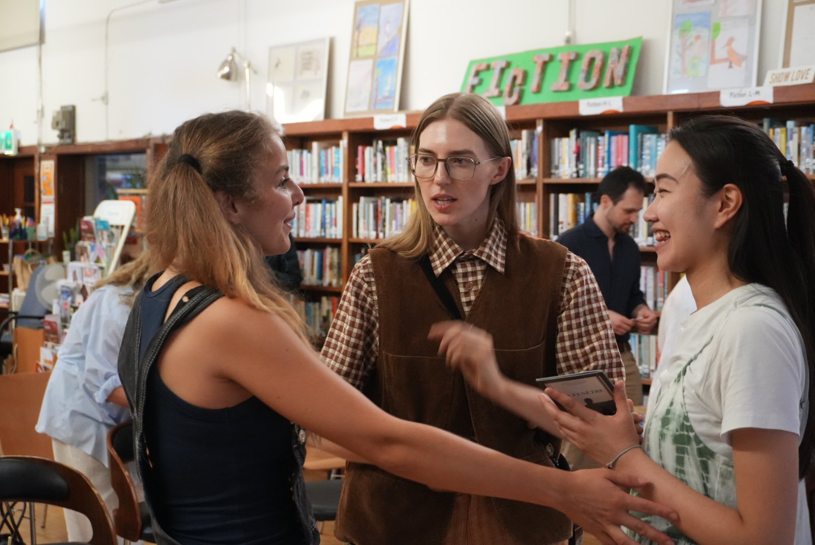 Performers and participants talking together in a library during a workshop.