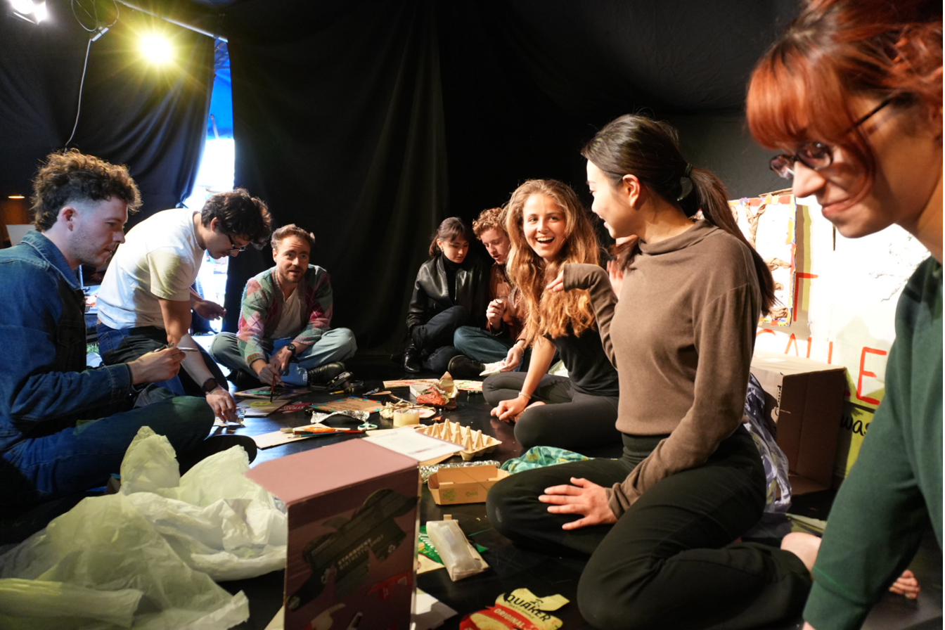 The company and workshop participants laughing together while making art from waste materials.